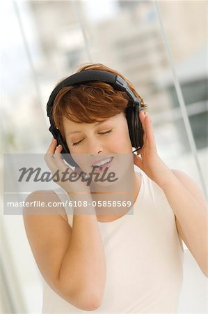 Portrait of a young woman, listening to music with headphones