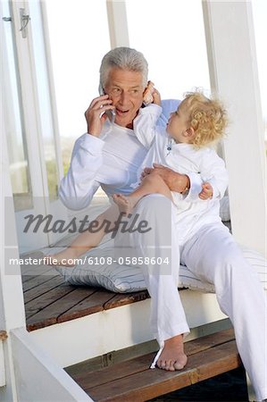 Alter Mann mit Handy, mit kleinen Jungen