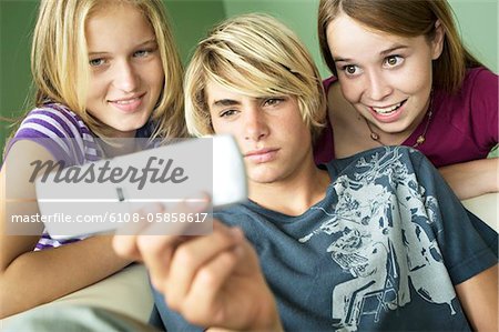 3 teenagers using camera phone