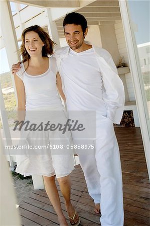 Smiling couple embracing, walking on wooden terrace