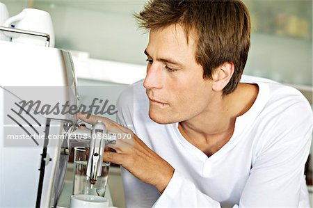 Jeune homme à l'aide de la machine à espresso