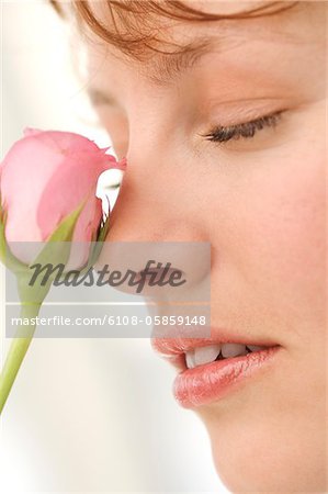 Portrait of young woman with rose in front of face, eyes closed