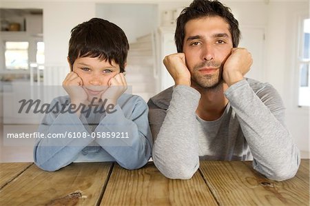 Father and son looking at camera, with hands on cheeks