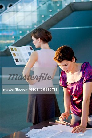 Mid femme adulte, établissant un plan d'action avec une jeune femme regardant un échantillon de couleur