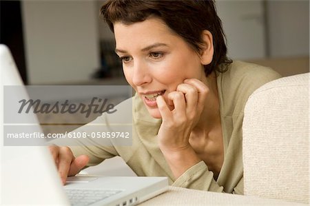 Mid femme adulte travaillant sur un ordinateur portable dans une salle de séjour
