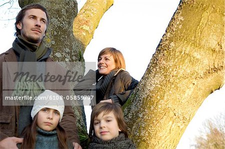 Two children standing near a tree with their parents