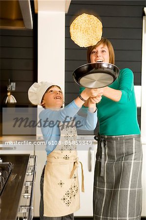 Young woman flipping a pancake with her son