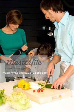 Mid adult man and a young woman preparing food with their son