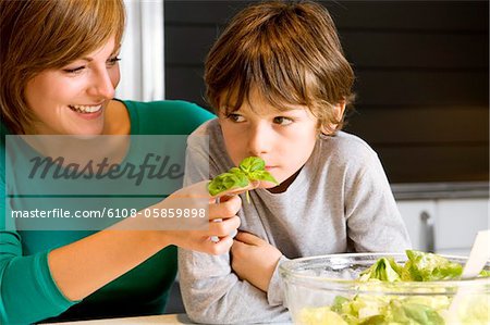 Gros plan d'une jeune femme alimentation basilic à son fils