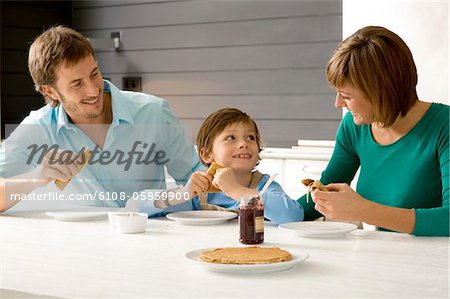 Mitte erwachsener Mann und eine junge Frau mit ihrem Sohn frühstücken