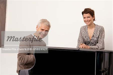 Portrait d'un homme mûr, un piano et une mid femme adulte debout près de lui