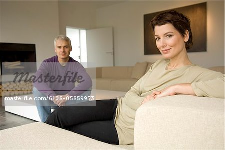 Porträt einer Frau des mittleren Alters und ein älterer Mann sitzt in einem Wohnzimmer