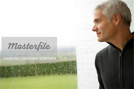 Close-up of a mature man looking out through a window