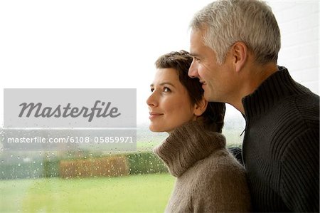 Frau mittleren Alters und ein älterer Mann am Fenster stehend