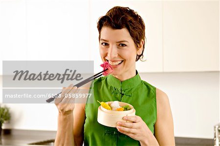 Portrait of a mid adult woman eating food with chopsticks