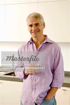 Portrait d'un homme d'âge mûr tenant un verre d'eau dans la cuisine