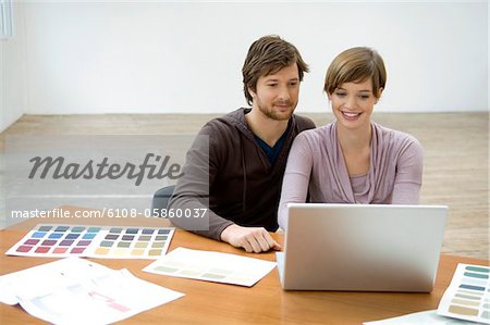 Mid homme adulte et une jeune femme à l'aide d'un ordinateur portable et souriant