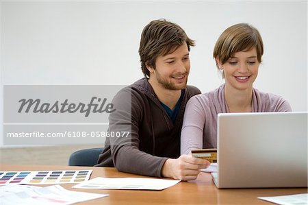 Mid homme adulte et une jeune femme à l'aide d'un ordinateur portable et maintenant une carte de crédit