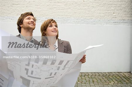 Mid adult man and a young woman holding a blueprint