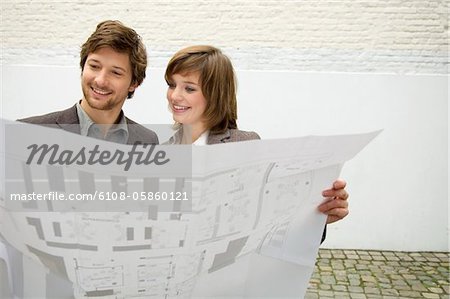 Mid adult man and a young woman looking at a blueprint