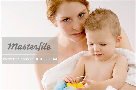 Portrait of a young woman wrapping her son in a towel and smiling