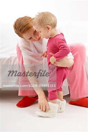 Jeune femme, mettre les chaussons à son fils