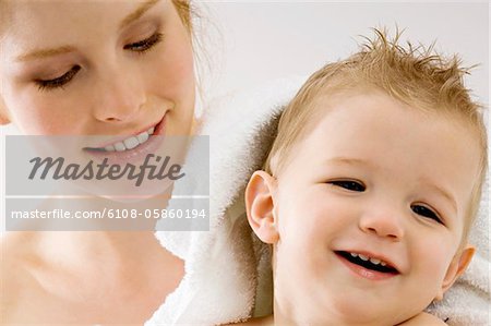 Close-up of a young woman wrapping her son in a towel and smiling