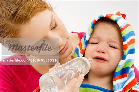 Nahaufnahme einer jungen Frau, die ihren Sohn weint aus einer Babyflasche Fütterung