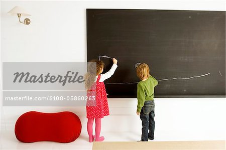 Two children drawing on a blackboard