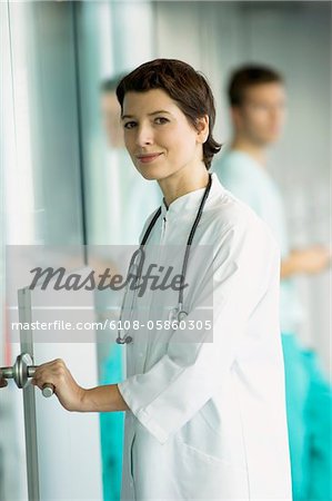 Portrait d'une femme médecin tenant une poignée de porte et souriant