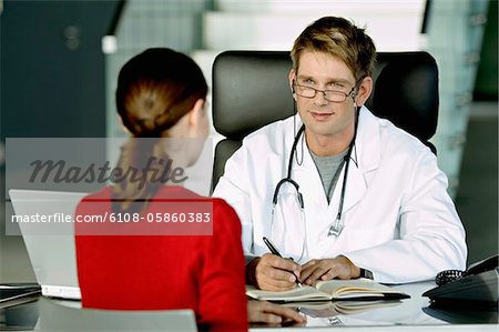 Männlichen Arzt diskutieren mit einer Patientin in seinem Büro