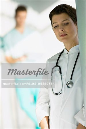 Female doctor leaning against a column and looking serious