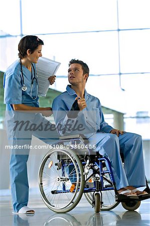Male patients assis dans un fauteuil roulant et en regardant une femme médecin debout derrière lui