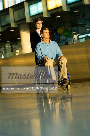 Young woman pushing a male patient sitting in a wheelchair