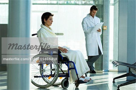 Female patient sitting in a wheelchair and a male doctor standing in the background