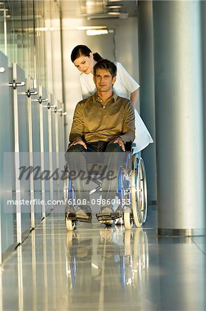 Female doctor pushing a male patient sitting in a wheelchair