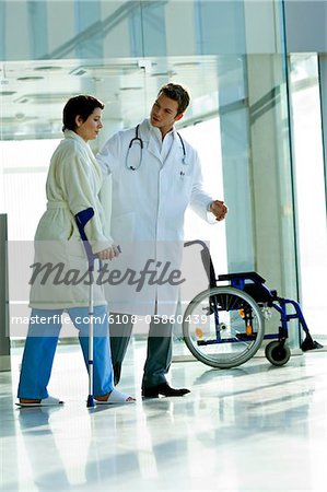 Männlichen Arzt bei eine Patientin, zu Fuß auf Krücken