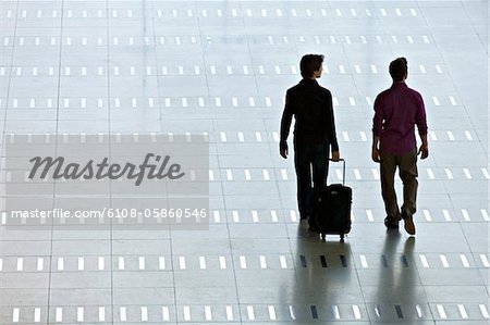 Rear view of two men walking at an airport lobby