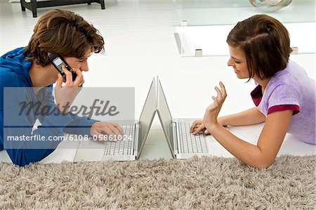 Teenage boy and a young woman using laptops