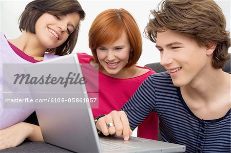 Close-up of two young women and a teenage boy looking at a laptop