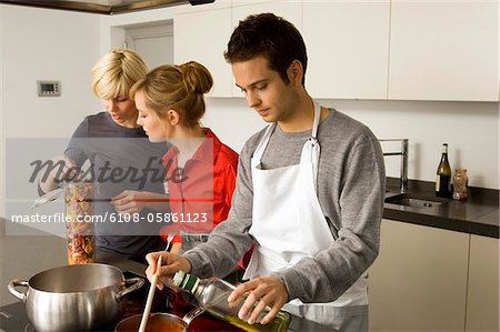 Deux jeunes femmes et un jeune homme, préparation de la nourriture dans la cuisine