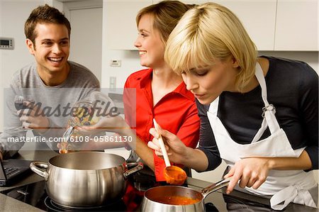 Two young women and a young man preparing food in the kitchen