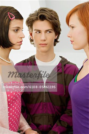 Close-up of a teenage boy standing with two young women