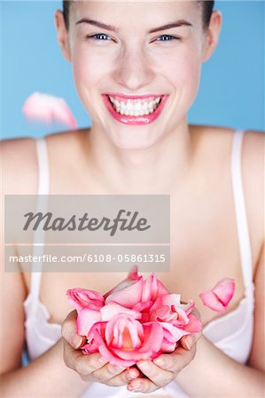 Young smiling woman holding rose petals