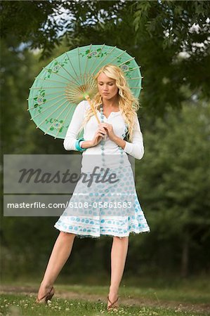 Junge Frau in einem Park, einen Regenschirm halten