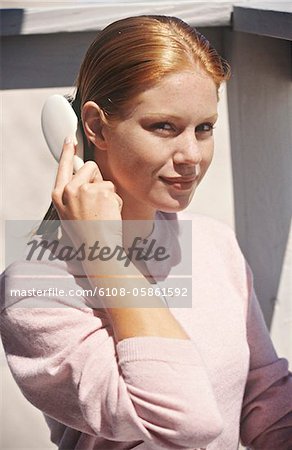 Jeune femme assise sur un balcon, se brosser ses cheveux