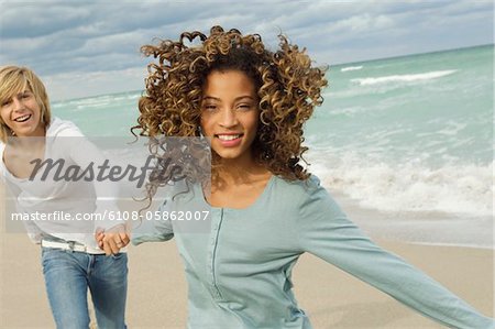Mädchen an der Hand von einem Teenager am Strand