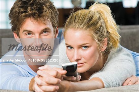 Portrait d'un couple tenant une télécommande et souriant