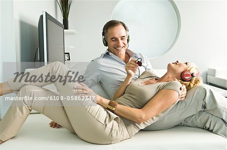 Couple à l'écoute de musique avec un casque et souriant