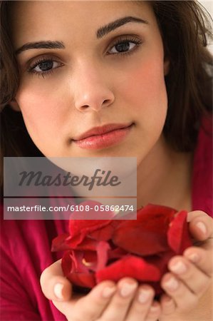 Portrait d'une femme tenant une poignée de pétales de rose rouges
